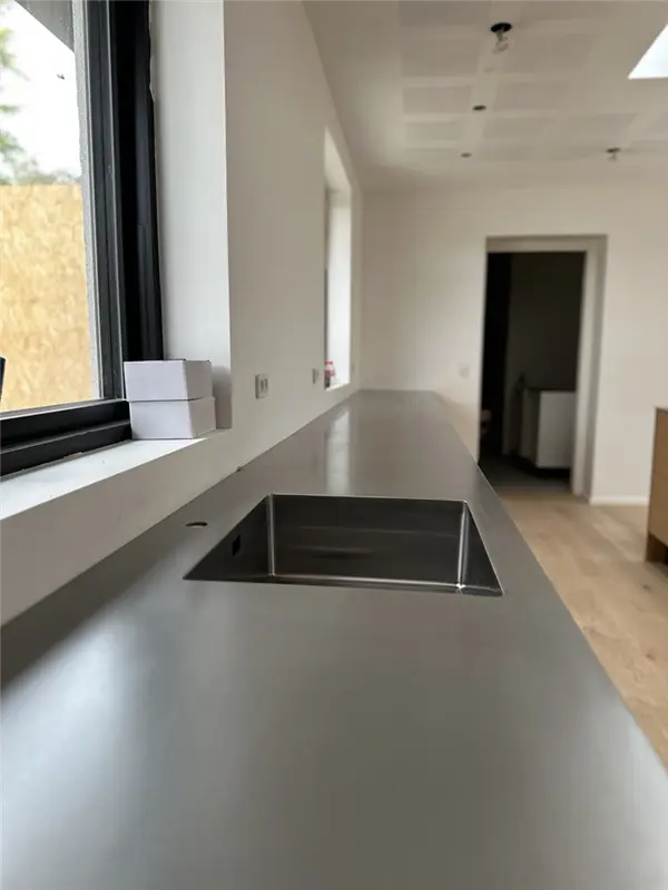 Stålbordplade med isvejst vask og hanehul set i perspektiv langs vinduet